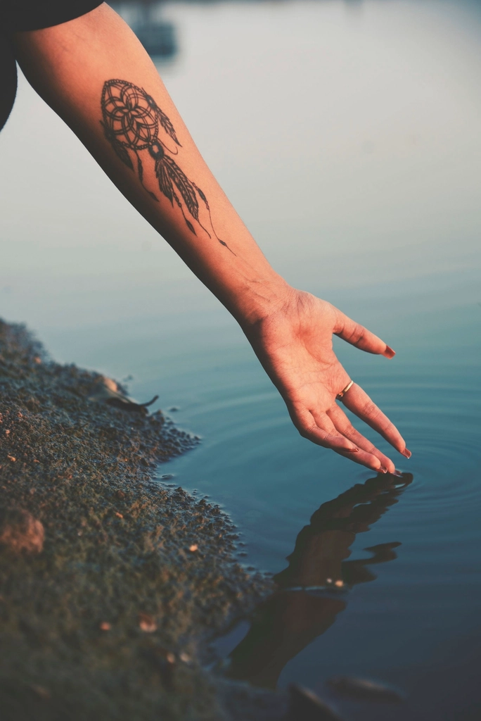 Feines Tattoo am Arm über dem Wasser